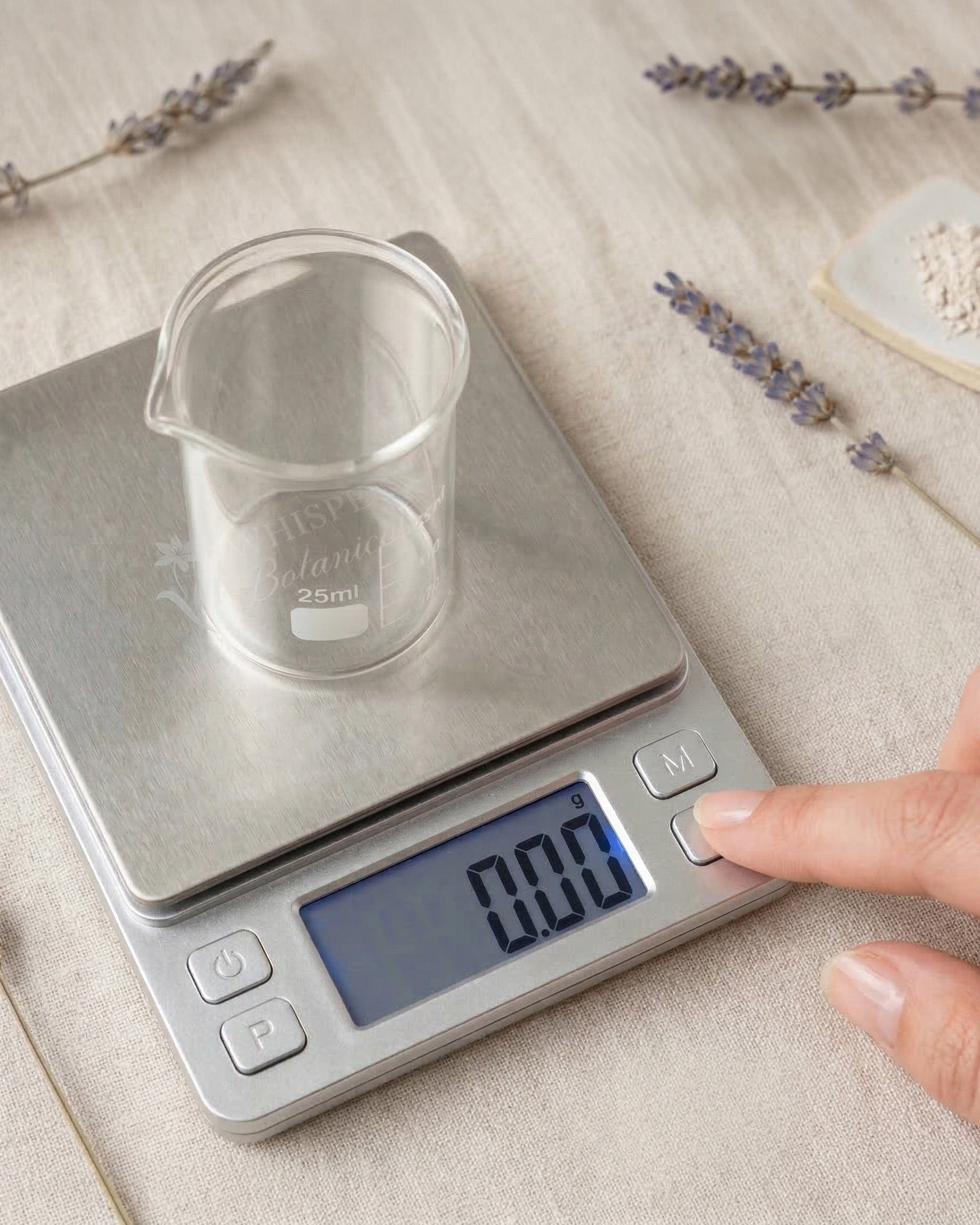 Digital kitchen scale with a clear measuring cup on a light surface with lavender flowers.